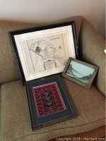 Framed map, painting and needlepoint displayed together on couch