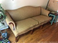 Full view of vintage gold upholstered sofa showing the overall shape, upholstery, and carved wood base and legs.