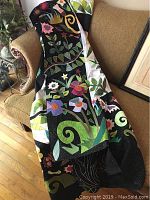 Quilt folded on couch showing colorful applique flowers on black and white background.