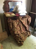 King size comforter and pillows displayed on a wooden dresser, detailing the intricate red and gold comforter and pillows on top.