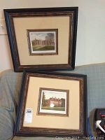 Photo showing both framed architectural prints leaning against a sofa, clearly displaying frames, mats, and print subject matter.