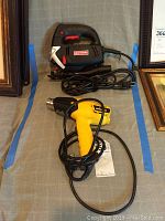 Both Craftsman jig saw and Wagner heat gun displayed side by side on a cloth surface