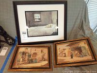 Three framed wall art pieces showing two vintage Egyptian watercolors and one Wyeth print on a gray cloth background.