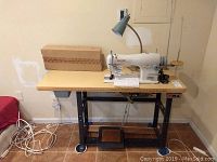 Full frontal view of sewing table showing machine, lamp, box