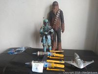 Wide view of the lot showing the two large action figures (Chewbacca and Boba Fett), two yellow starfighters, a silver starfighter, and a cloth accessory piece.