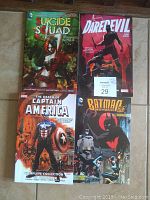 Photo of 4 trade paperback comic books laid out on a surface showing covers of Suicide Squad, Daredevil, The Death of Captain America, and Batman Beyond 2.0