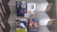 Front covers of four rock biography books displayed on carpeted stairs.