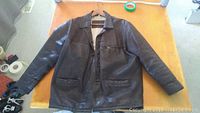 Front view of brown Akaso leather jacket showing zipper, three pockets, and collar detail.