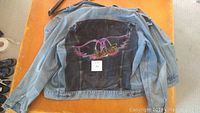 Full rear view of the denim jacket showing the large airbrushed Aerosmith logo artwork across the back.