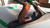 Side view showing the wooden handle and metal base of the antique hand planer.