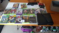 Full lot showing Xbox 360 console, Kinect sensor, two controllers, and multiple game discs on a white table.