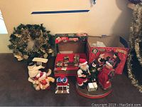 Four holiday-themed items: dancing Claus couple figurine, Holiday Carousel boxed ornament, singing dancing chicken plush, piano-playing snowman figurine captured in one photo.