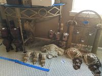 Photo of assorted candle holders and decorative elements spread on carpet, showing dark wood candle holders, carved wooden pieces, shelf brackets, and large wall hanging candle holder.