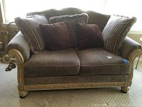 Full front view of the Ashley Furniture brown corduroy love seat with all seven pillows arranged on backrest.