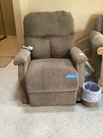 Full view of the brown fabric electric lift recliner chair showing padded armrests, cushioned back and seat, and fabric wear