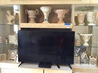 Ceramic and resin urns, busts, and decorative pieces displayed on shelves around a TV (TV not included).