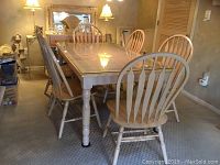 View of dining table surrounded by six matching wood chairs in room setting.