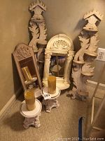 Photo showing the full set of sconces, mirrors, and candle pedestals grouped together on carpet against a wall.