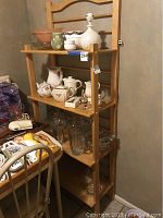 Wide view of wooden shelving unit displaying array of clear cut glass vases, pitchers, ceramic tea pots, smaller bowls, and various glass pieces