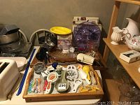 Overview of kitchen utensils and appliances on a wooden tray and surface including Pizzelle Baker and hand mixer