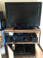 Front view of Emerson flat screen TV on media cabinet with RCA Blue Ray disc surround sound system including subwoofer and two satellite speakers below the TV.