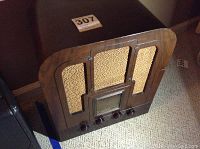 Full view of the wooden cabinet radio with fabric-covered speaker grilles and front control knobs.