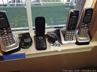 Four VTech cordless telephones and one flip phone on a window ledge