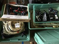 Multiple power cords, power strip surge protectors, RCA cables, and power adapters organized in green plastic bins and boxes