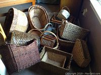 Photo showing a variety of woven baskets of different shapes and sizes grouped together on the floor and near a window.
