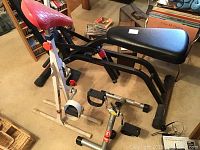 Lifestyler Cardiofit foldaway exerbike with red seat and white frame with black exercise bench on beige carpet indoor.