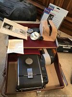 Polaroid Land Camera with accessories including flash, manuals, and case interior showing camera and components.