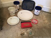 Photo showing assortment of Delta Airlines mugs, plates, small cup, and red pouch with Delta logo on carpeted floor.