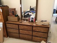 Front view of wooden dresser showing nine drawers with the surface holding some items (not included).