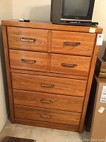 Full view of wooden chest of drawers showing five drawers and metal handles