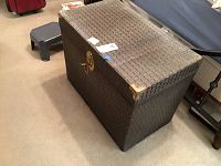 Exterior photo of closed dark-patterned vintage trunk with brass corners and latch on carpeted floor