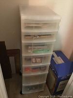 Plastic translucent shelving unit with multiple drawers filled with various small items.