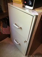 Photo of light gray metal two-drawer file cabinet with pull handles and key lock on lower drawer with key inserted.