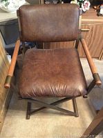 Front view of brown faux leather chair showing cushioned seat and back, wooden armrests, and steel frame.