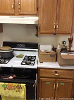 Kitchen scene showing small toaster oven on stove, cardboard boxes, drawer and cabinet storage with additional kitchen contents