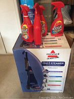 Boxed Bissell Quick Steamer PowerBrush deep cleaner with three bottles of Resolve carpet cleaning sprays on top.