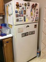 Front view of white Hotpoint refrigerator covered with magnets and notes.