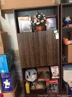 Full view of laminate bookshelf with center cabinet and various contents on shelves and below