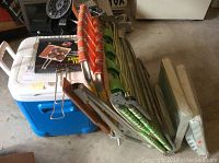 View of all items in the lot including cooler, folding chairs, tables, and grill basket.