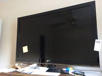 Front view of the LG 42 inch LED TV showing the screen, bezel, and stand, sitting on a desk with papers.