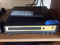 Front view of black and yellow JSI DVD player with remote control on top.