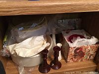 Contents of wooden drawer showing plastic containers, bags, and two wooden candlesticks
