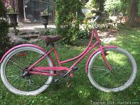 Full left-side view of pink step-through frame bicycle on grass