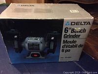 Photo of original box showing full image of Delta 6 inch bench grinder with guard, spark deflectors, and motor. Box labeled with brand and 6 inch bench grinder text.