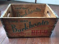 Full view of the wooden crate showing inside and front side with printed logo and text leading 'Since 1880 Burkhardt's mug ale & BEER'.