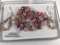 Boxed set showing a sterling silver bracelet and matching earrings with genuine pink tourmaline gemstones along with label indicating 'STERLING SILVER GENUINE GEMSTONE Genuine Tourmaline'.